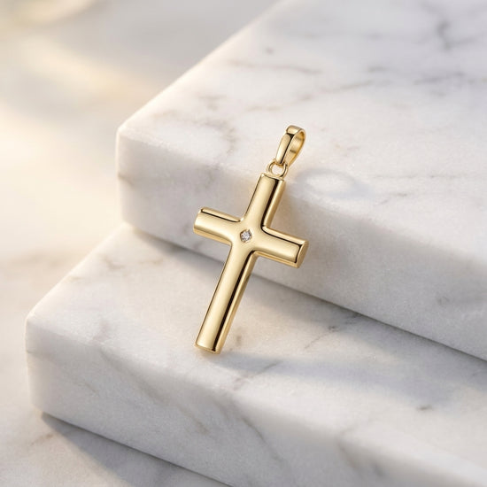 Goldener Kreuzanhänger mit Diamant in der Mitte auf weißem Marmor, polierte Oberfläche, Aurevia Manufaktur