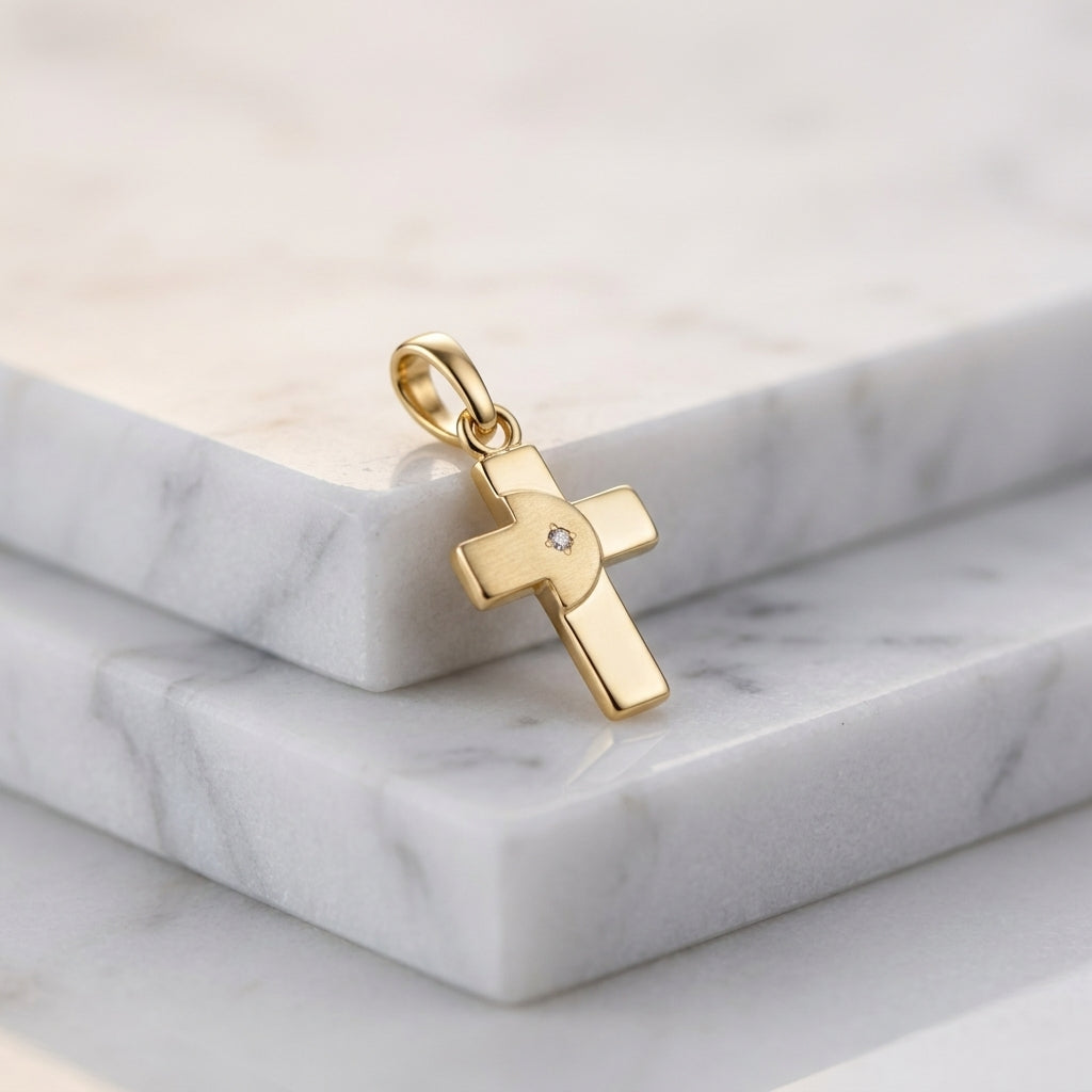 Goldener Kreuz-Anhänger mit funkelndem Zirkonia in der Mitte, auf weißem Marmor präsentiert