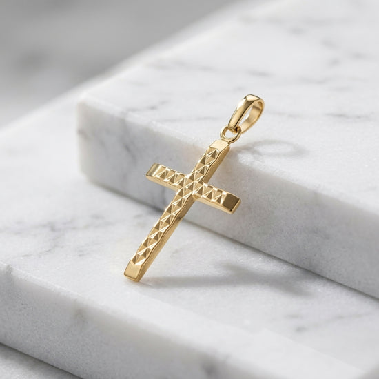 Goldener Kreuz-Anhänger mit geometrischem Tweed-Muster auf weißem Marmor, handgefertigt aus 585er Gelbgold