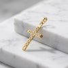Goldener Kreuz-Anhänger mit geometrischem Tweed-Muster auf weißem Marmor, handgefertigt aus 585er Gelbgold