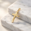 Goldener Kreuz-Anhänger Beam mit gebürsteter Oberfläche und polierten Kanten auf weißem Marmor