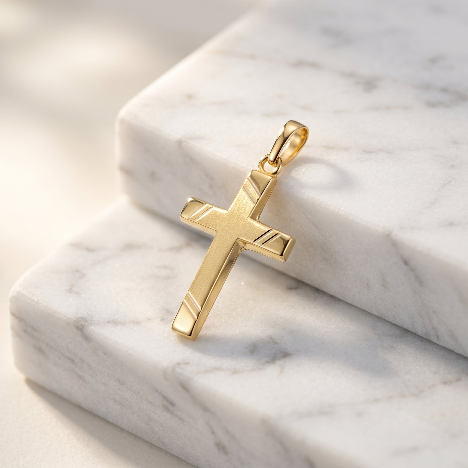 Goldener Kreuz-Anhänger Beam mit gebürsteter Oberfläche und polierten Kanten auf weißem Marmor
