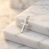 Silberner Kreuz-Anhänger Beam mit diagonalen Linien auf weißem Marmor, poliertes Edelmetall mit strukturierter Oberfläche
