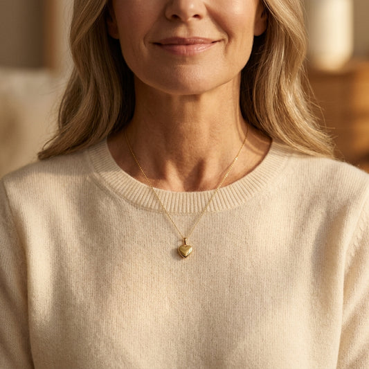 Frau trägt goldenes Herz-Medaillon Pure Petite an feiner Kette über cremefarbenem Pullover