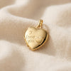 Goldenes Herz-Medaillon mit Gravur "I love you" und kleinem Herz, aufklappbar, auf cremefarbenem Stoff