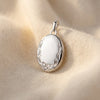 Ovales Silber-Medaillon mit weißer Emaille-Front, verziert mit filigranen Ranken und Schmetterling-Detail auf Samt