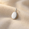 Silbernes Oval-Medaillon Pure Mini mit polierter Oberfläche auf cremefarbenem Stoff