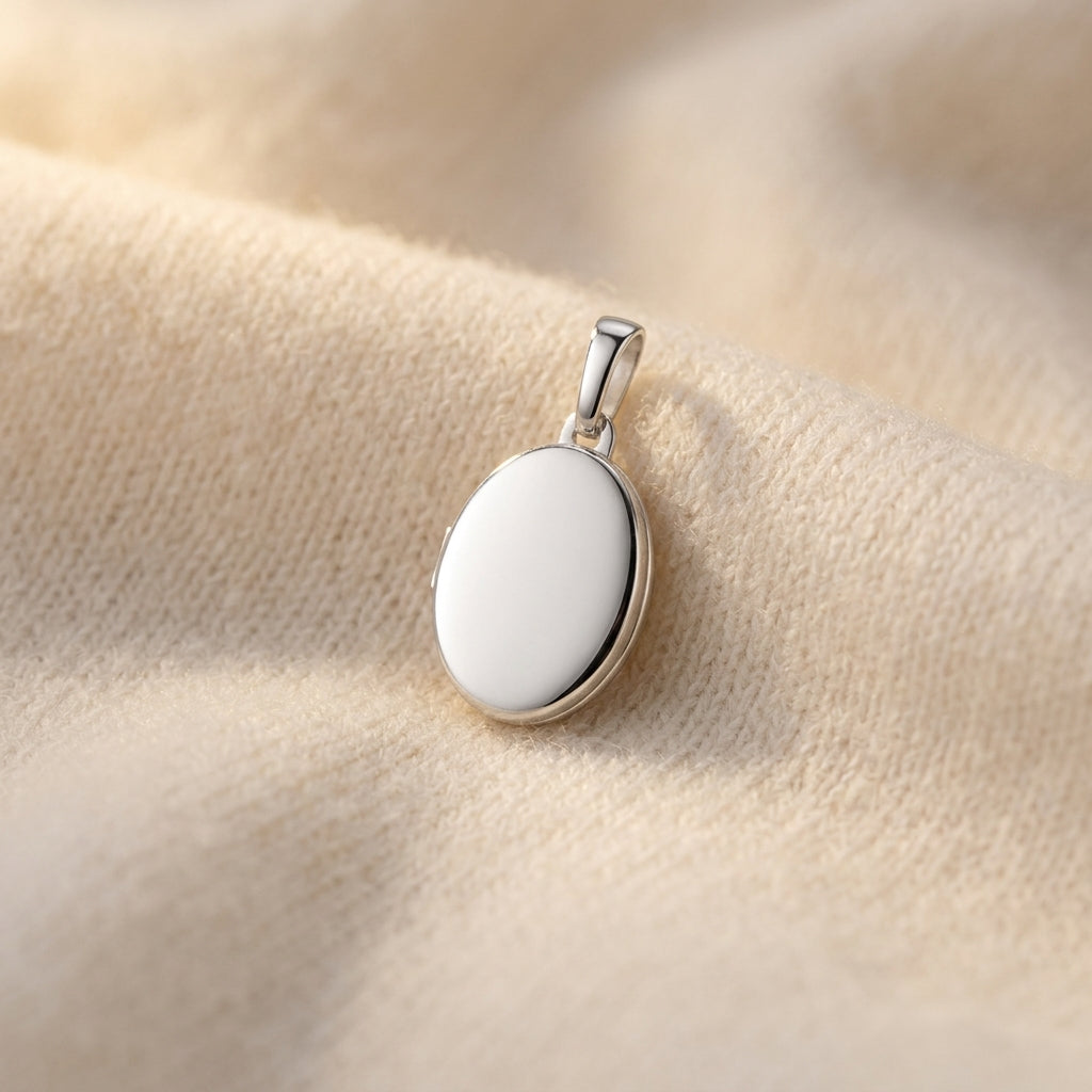 Silbernes Oval-Medaillon Pure Mini mit polierter Oberfläche auf cremefarbenem Stoff