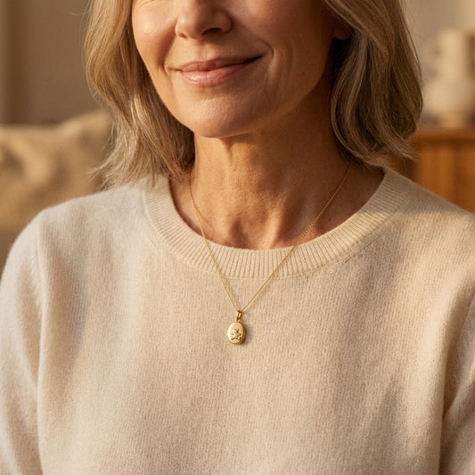 Goldenes Oval-Medaillon mit Teddy-Gravur an feiner Kette, getragen von lächelnder Frau in beigem Pullover