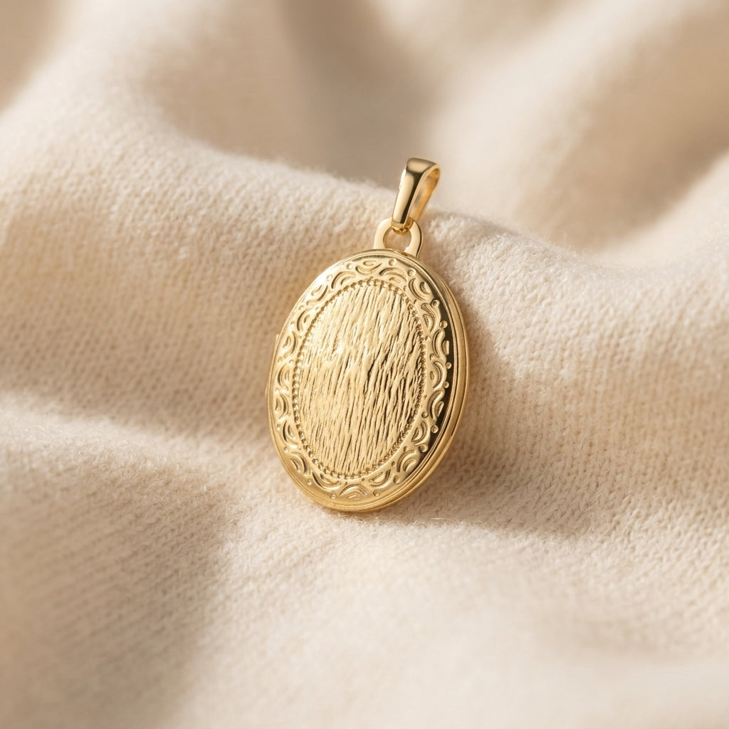 Goldenes Oval-Medaillon mit gravierter Oberfläche und ornamentaler Umrandung auf cremefarbenem Seidenstoff