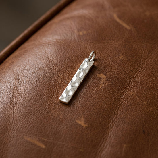 Silberner Stab-Anhänger Reed mit gehämmerter Oberfläche auf braunem Leder